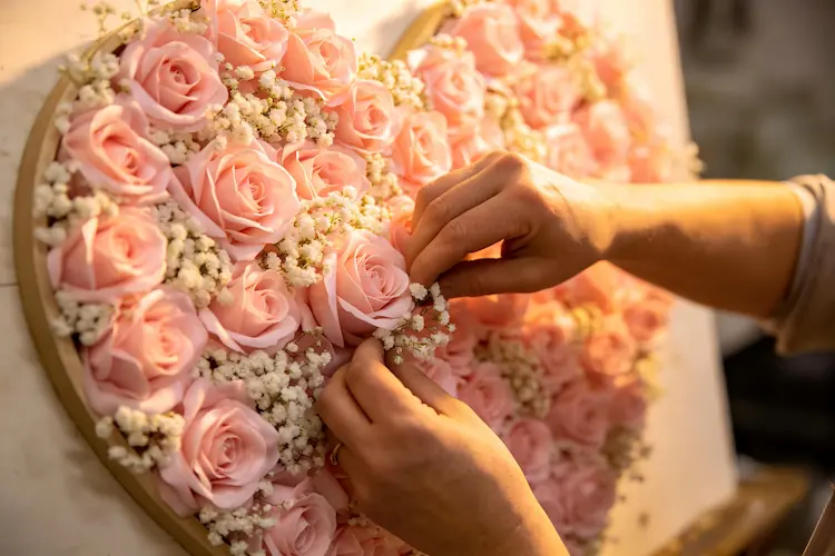 artisan handcrafting pink heart shaped flower wall